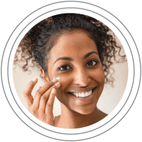 Skincare: Woman applying moisturizer and smiling at the camera