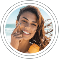 Sun Care: Woman applying sunscreen and smiling at the camera